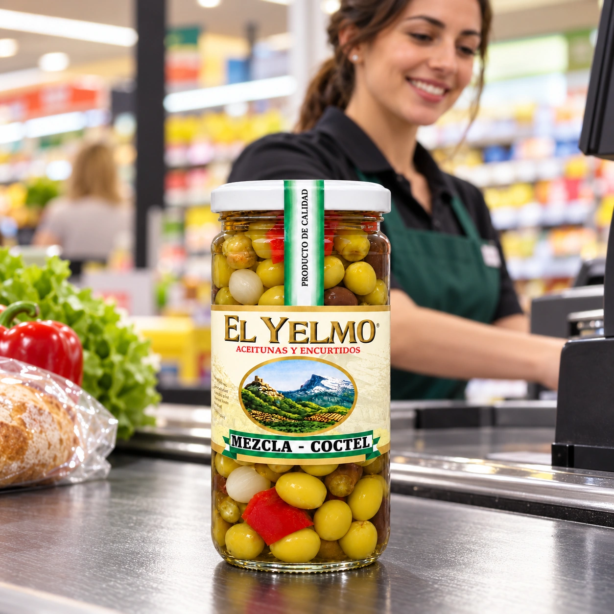 Tarro de aceitunas cóctel El Yelmo sobre un mostrador de supermercado, con una cajera al fondo.